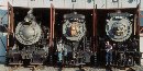Three steam locomotives are visible in the doors of a roundhouse. Three steam locomotives are visible in the doors of a roundhouse.