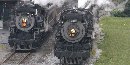 Two steam locomotives pulling passenger trains pass by the loading platform at Steamtown. Two steam locomotives pulling passenger trains pass by the loading platform at Steamtown.