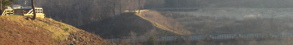 A view of the South and North abutments of the South Fork Dam.  The Visitor Center, Unger House, and Spring House are visible in the background.  As is visible, a spur railroad line connects coal trains with the main line of the railroad.