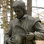 Bronze statue of man holding hat