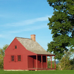 A small, red, one-room farmhouse.