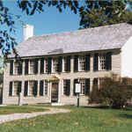 A pale yellow, stately yet simple two-story historic house.