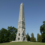 A tall, stone obelisk reaches into a clear, cool sky.