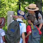 Ranger at trailpost with 3 young visitors.