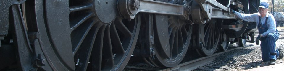 An engineer inspects the running gear of a steam locomotive at Steamtown NHS