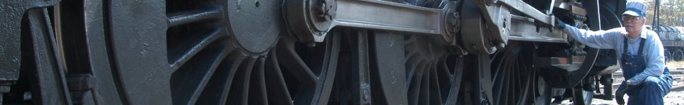 An engineer inspects the running gear of a steam locomotive at Steamtown NHS
