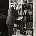 Carter G. Woodson standing by bookcase
