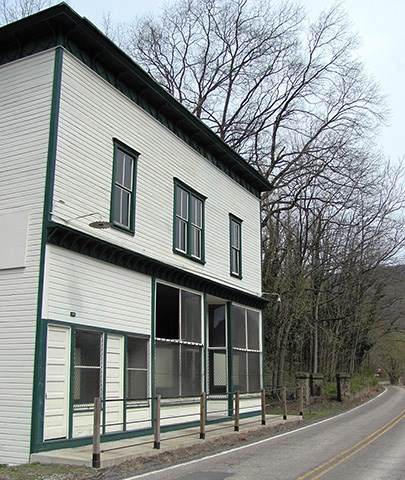 A white building with green trim next to a paved road