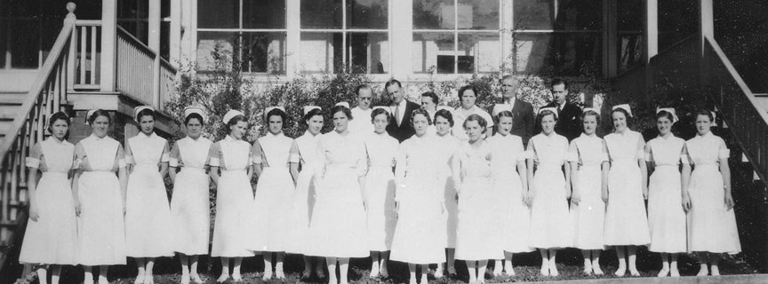 nurses in white dresses standing on the steps in front of an old hospital