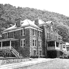 Historic photo of a large three story brick building with two covered porches