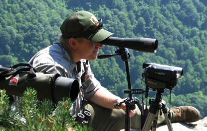 Wildlife biologist using spotting scope to monitor peregrine falcon activity.