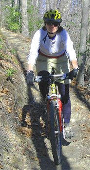 Woman riding mountain bike down 2-foot wide trail.