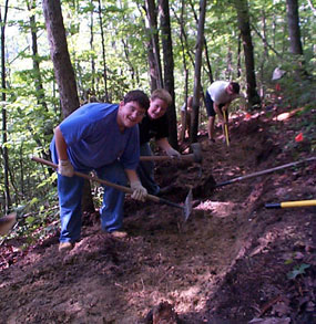 Volunteers hard at work usign handtools to bench in a new section of trail