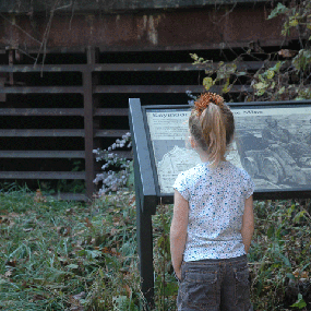 young girl stands in front of mine entrance