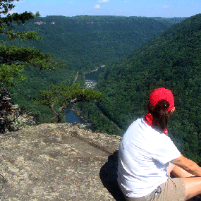 Hiker sitting on a cliff edge overlooking the New River