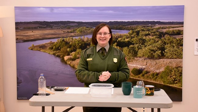 A ranger stands at a table with cups and bowls.