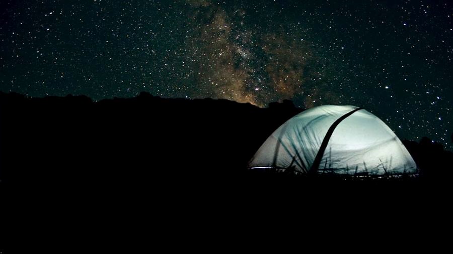 Tent on river bank under a blanket of stars.