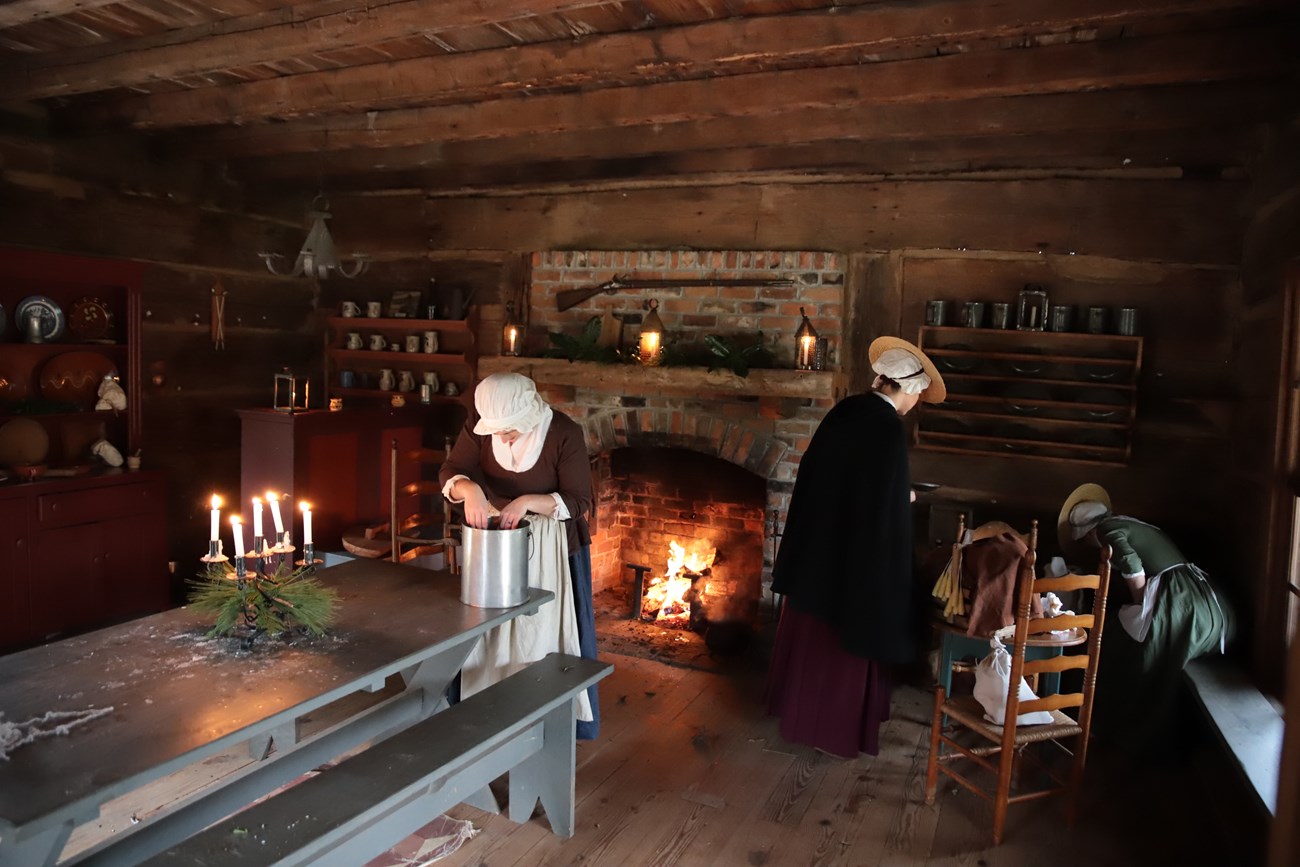 Colonial women working in a log house.