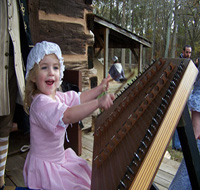 A little girl plays the hammer dulcimer.