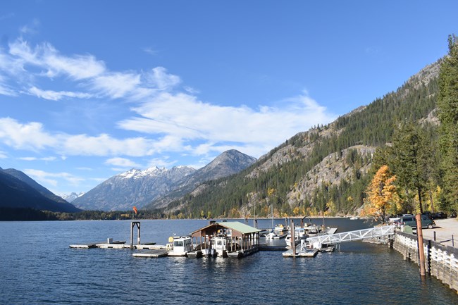 A marina with a few boats on a lake with mountains in the background