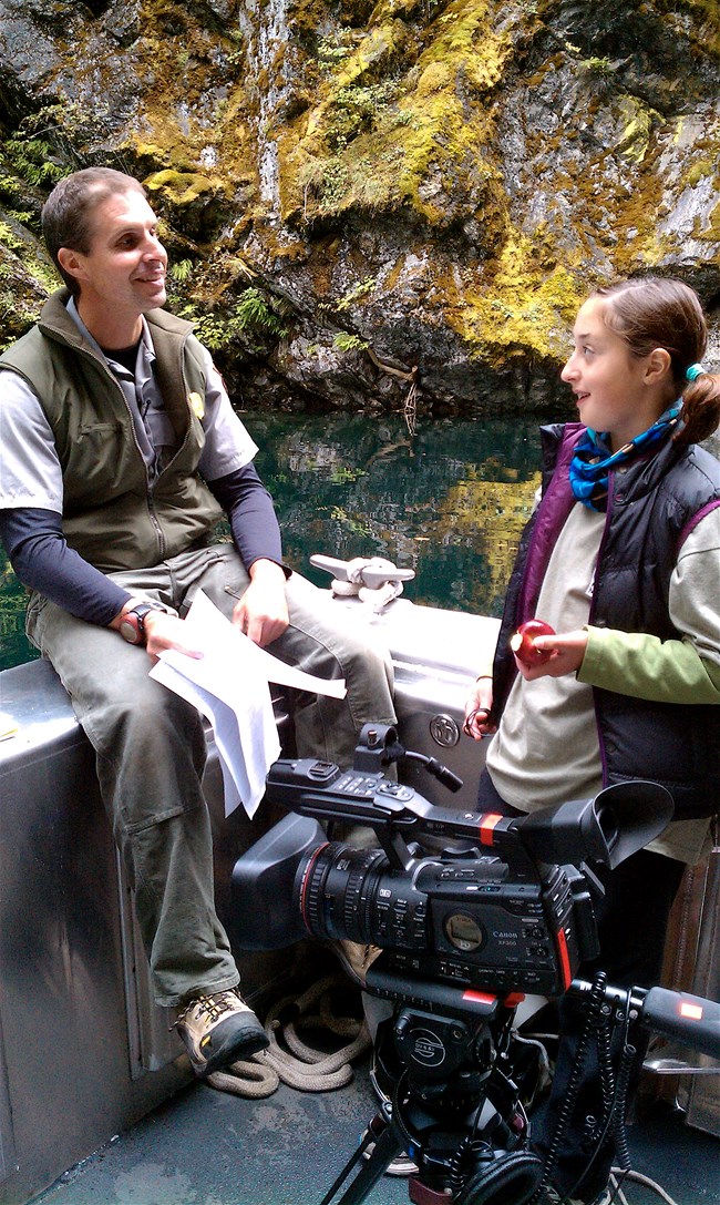 A film maker and a child on a boat with a camera