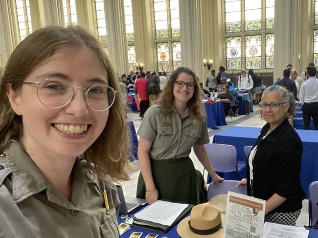 Three NPS employees pose for a photo in a large open room