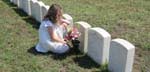 Photo of a young girl placing flowers on a grave