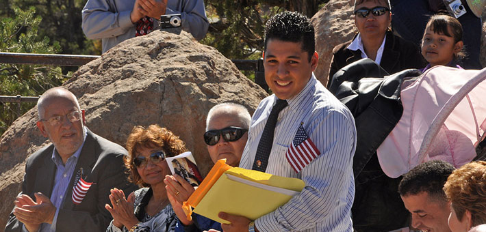 Young man with American flag in shirt pocket smiles at naturalization ceremony
