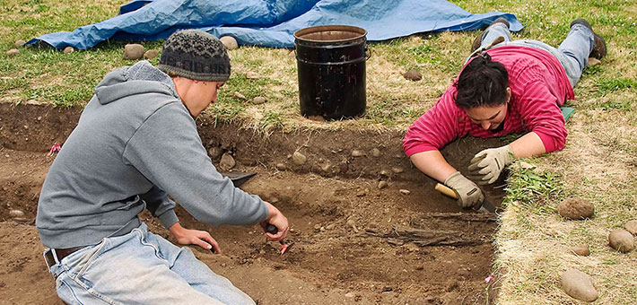 Students use hand tools to excavate an archeological site