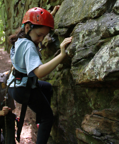 Little girl maneuvering on rock wall learning how to climb
