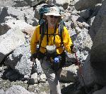 man in yellow with hiking poles