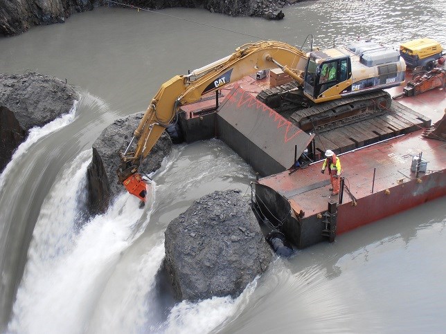 barge with excavator mounted on it next to a dam