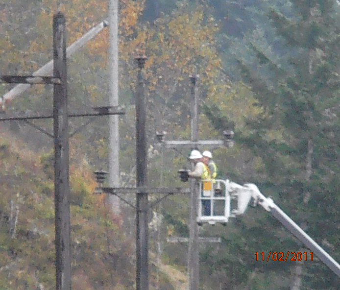 workers removing insulators from a power pole