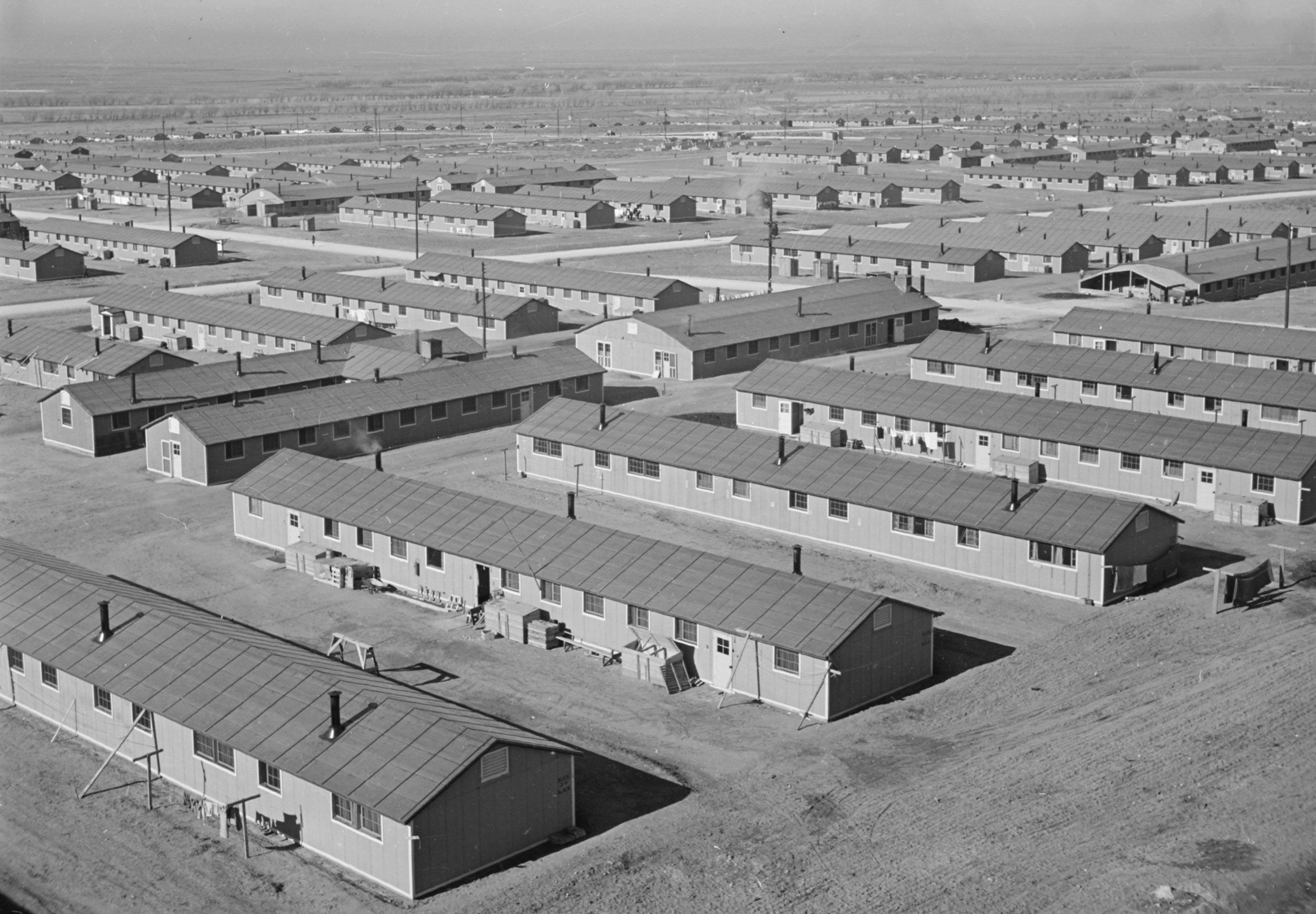 Black and white photo of rows and rows of low, bare, one-story buildings.