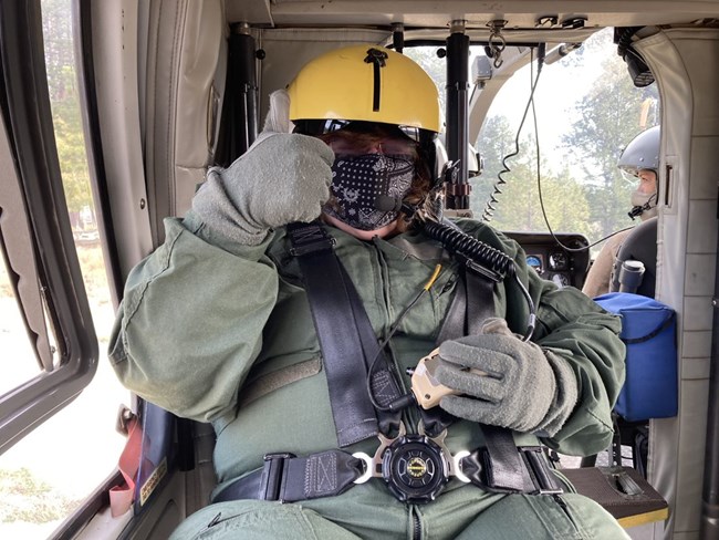 NPS Employee in flight attire gives a "thumbs up" while traveling by aircraft.