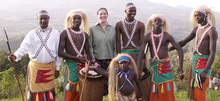 An NPS Concessions Specialist with a group of Rwanda dancers who are dressed in colorful native garb.