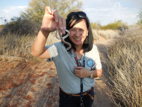 Teacher-Ranger-Teacher holding a small snake in the field