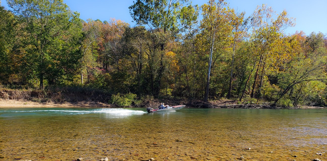 A jet boat glides across the surface of a river.