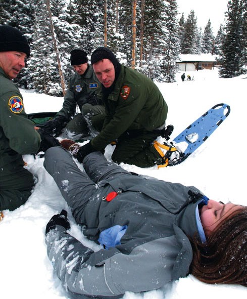 Rangers attending to a lady laying in the snow with apparent injury