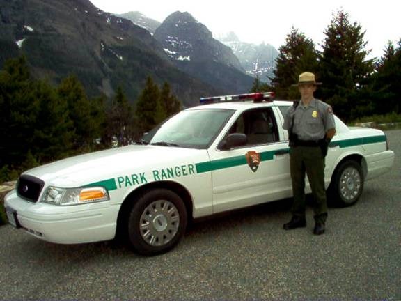 Park Ranger standing by his patrol vehicle with mountains is the distance