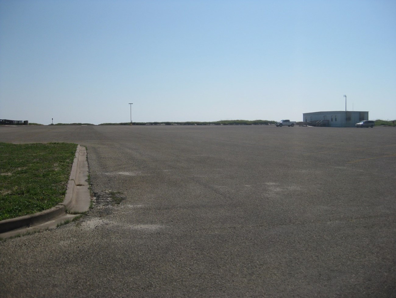 A large open parking lot with a small building on the far side.