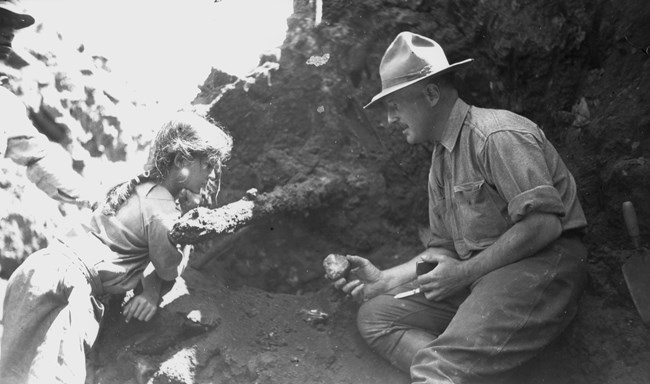 man and young girl looking at pot sherd