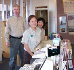 Charles, Marie, and Jin Hewett work as volunteers at the visitor center desk.