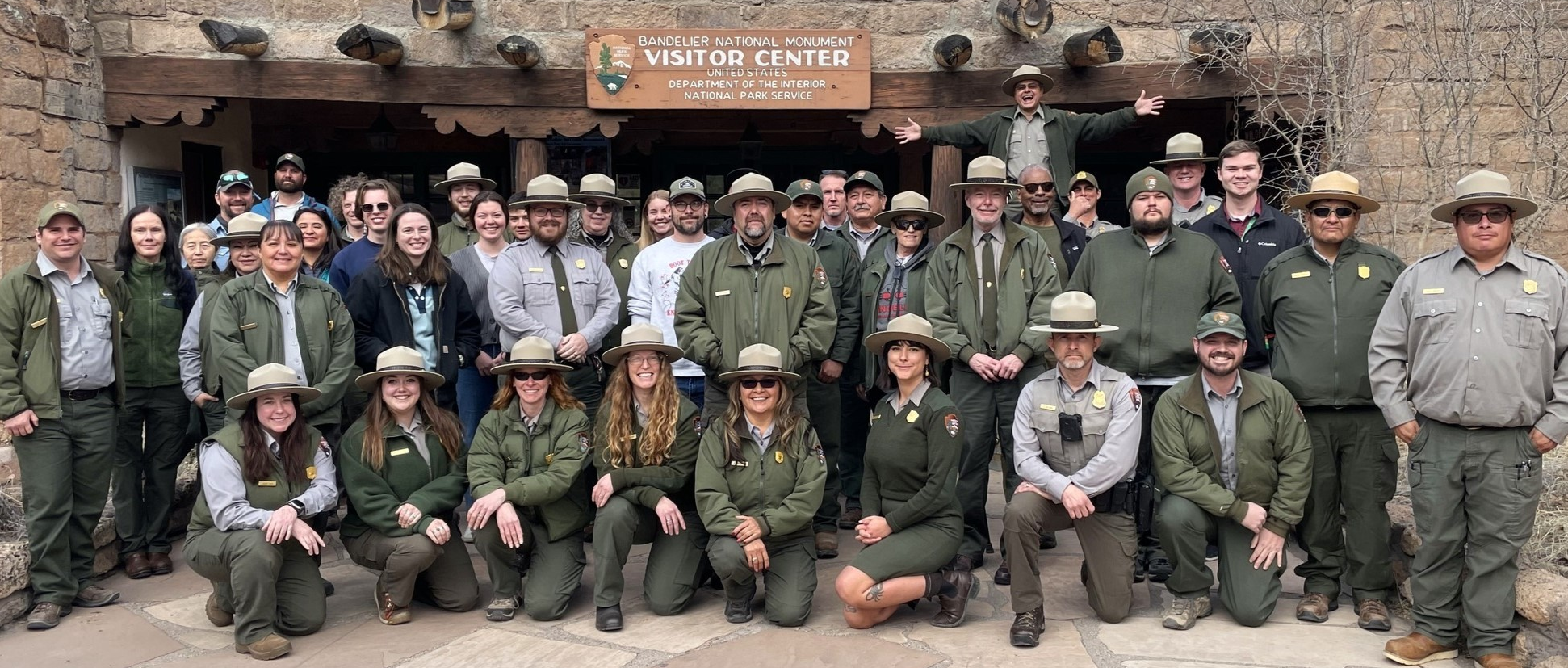 A group of uniformed employees stand in front of a visitor center