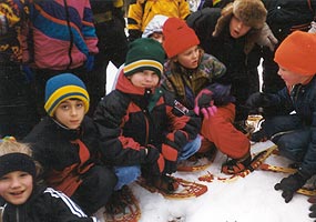 Children pause to explore while on a snowshoe field trip.