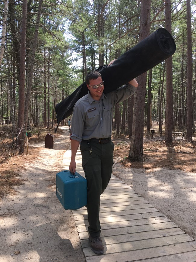 Employee carrying equipment on a trail
