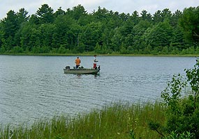 Two visitors are shown fishing from their boat on an inland lake at Pictured Rocks National Lakeshore. They forgot to wear their personal flotation devices!