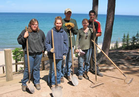 Five Youth Conservation Corps enrollees with their rakes and shovels on the trail above Miners Beach.