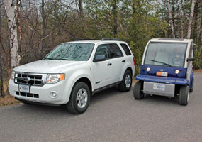 This white Ford Escape SUV is a hybrid vehicle. The smaller Ford Think Neighbor is an electric vehicle.