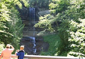 Visitors on a lookout view Munising Falls as the sun shines through on the trees. Visitors on a lookout view Munising Falls as the sun shines through on the trees.